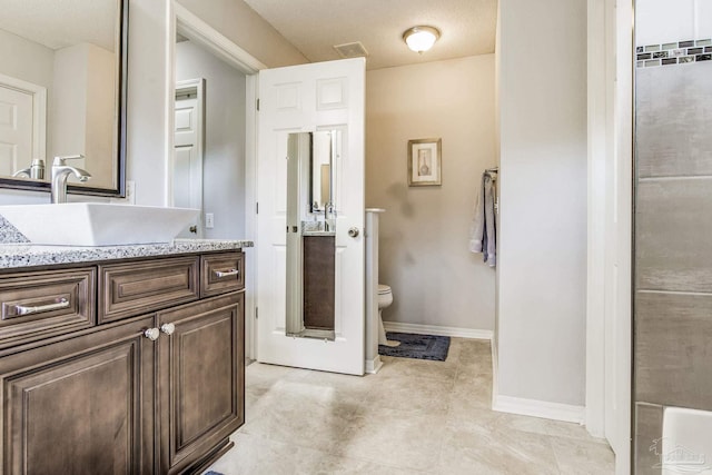 bathroom with a textured ceiling, vanity, and toilet