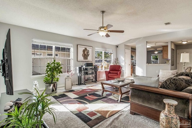 living room with light carpet, ceiling fan, and a textured ceiling