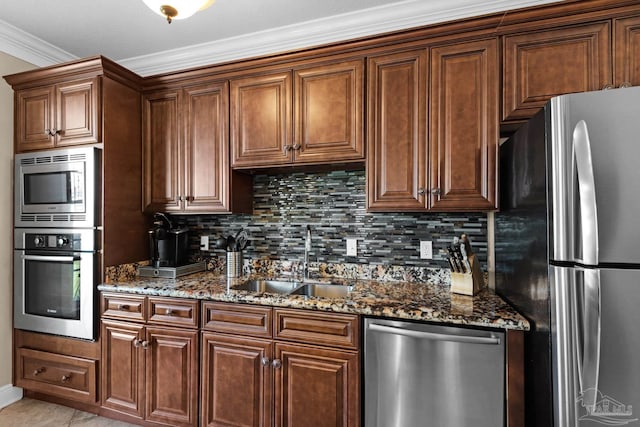 kitchen with ornamental molding, dark stone counters, sink, and stainless steel appliances