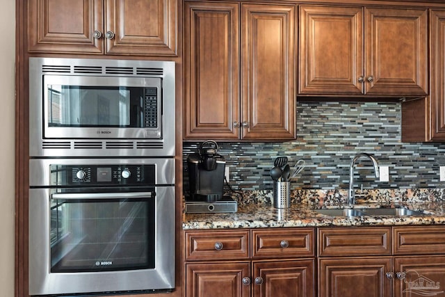 kitchen featuring tasteful backsplash, dark stone counters, appliances with stainless steel finishes, and sink