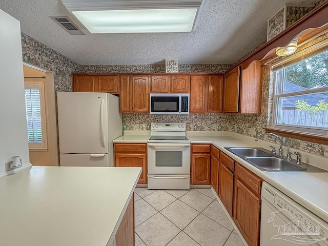4514 Southpointe Ln, Pensacola, FL 32514 - kitchen featuring white appliances, a sink, brown cabinetry, light tile patterned flooring, and a textured ceiling