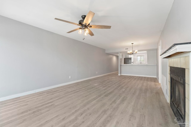 14100 River Rd Unit 223B, Pensacola, FL 32507 - unfurnished living room with a chandelier, a fireplace, light wood finished floors, baseboards, and ceiling fan