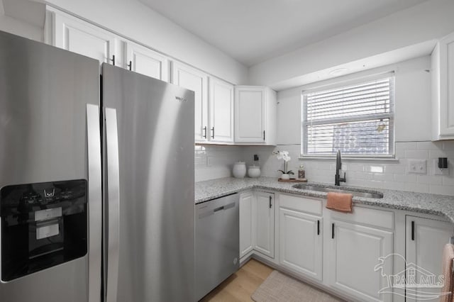 kitchen with backsplash, sink, white cabinets, and stainless steel appliances