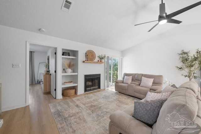 living room featuring built in shelves, ceiling fan, light hardwood / wood-style floors, and lofted ceiling