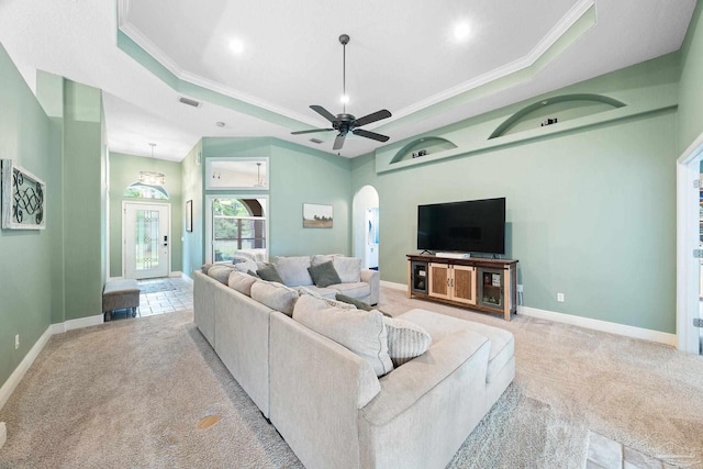 carpeted living room featuring ceiling fan, ornamental molding, and a tray ceiling