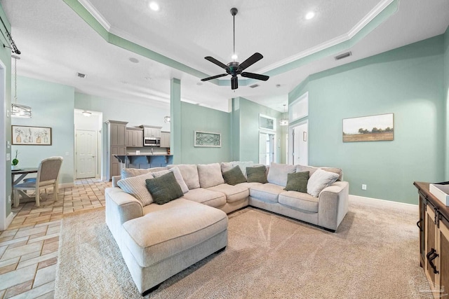 living room with crown molding, a tray ceiling, and ceiling fan