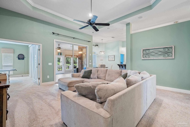 living room featuring a raised ceiling, crown molding, light colored carpet, and ceiling fan