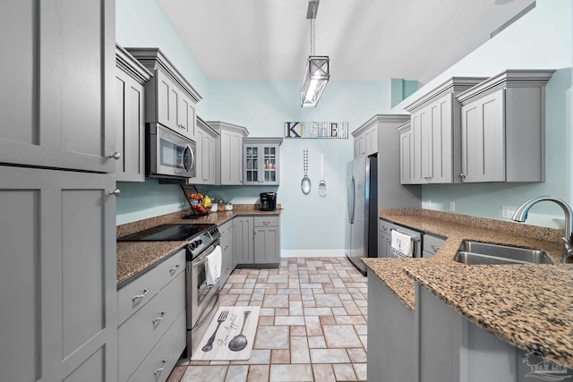 kitchen featuring sink, gray cabinetry, decorative light fixtures, dark stone countertops, and appliances with stainless steel finishes