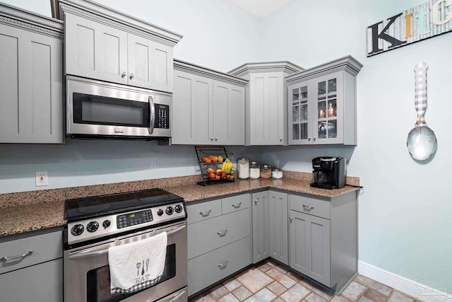 kitchen featuring dark stone countertops, stainless steel appliances, decorative light fixtures, and gray cabinetry