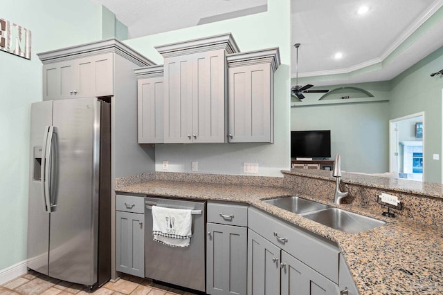 kitchen with sink, appliances with stainless steel finishes, a tray ceiling, ornamental molding, and ceiling fan