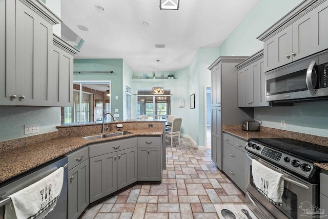 kitchen with appliances with stainless steel finishes, decorative light fixtures, gray cabinets, and sink