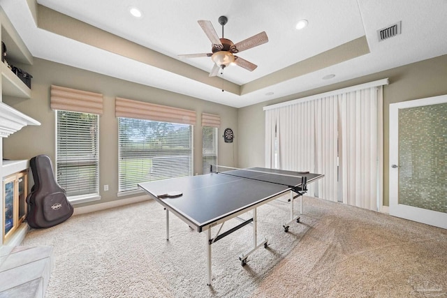 recreation room with a tray ceiling, ceiling fan, and carpet