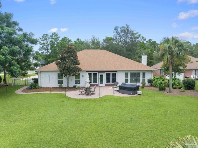 back of property featuring a patio area, a hot tub, and a lawn