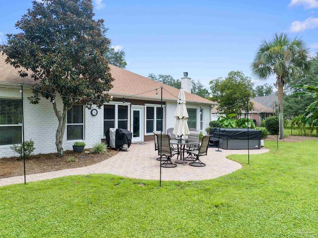 rear view of property with a patio area, a hot tub, and a lawn