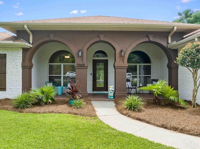 entrance to property featuring a yard and covered porch