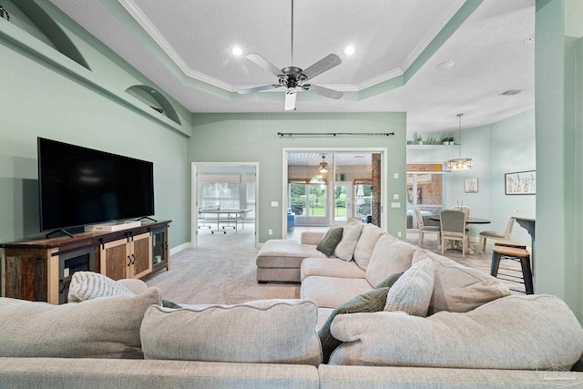 living room featuring crown molding, a tray ceiling, carpet floors, and ceiling fan