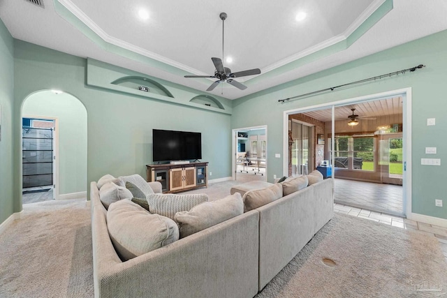 living room featuring crown molding, a tray ceiling, light colored carpet, and ceiling fan