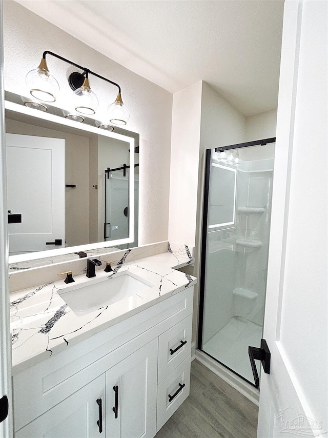 bathroom with hardwood / wood-style floors, vanity, and walk in shower