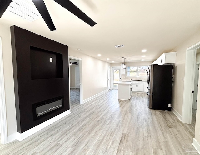 kitchen featuring a kitchen island, pendant lighting, light hardwood / wood-style flooring, white cabinets, and stainless steel refrigerator