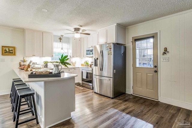 2519 Inda Ave, Pensacola, FL 32526 - kitchen with wood finished floors, appliances with stainless steel finishes, a peninsula, and white cabinetry
