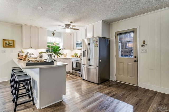 2519 Inda Ave, Pensacola, FL 32526 - kitchen with light countertops, a peninsula, wood finished floors, white cabinets, and stainless steel appliances