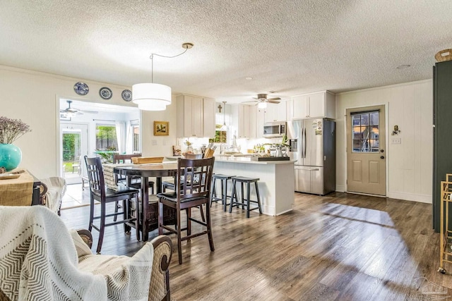 dining space featuring a textured ceiling, dark hardwood / wood-style flooring, and crown molding