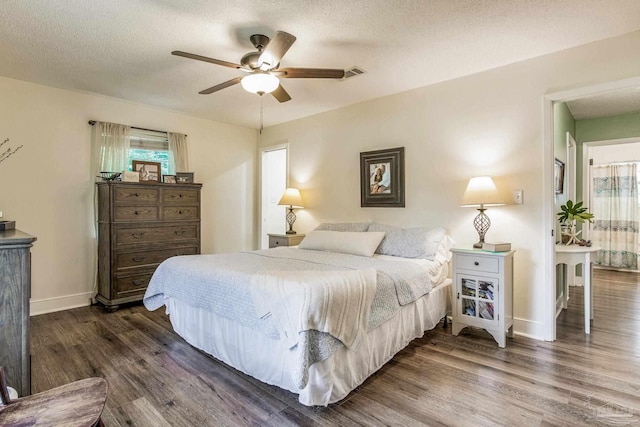 bedroom with ceiling fan, dark hardwood / wood-style floors, and a textured ceiling