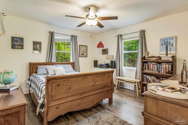 bedroom with ceiling fan, dark wood-type flooring, and a textured ceiling