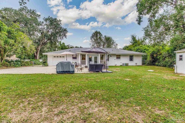 back of house with a lawn, a garage, and a patio