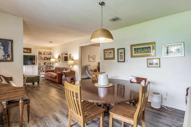 dining space featuring built in shelves, a textured ceiling, and wood-type flooring