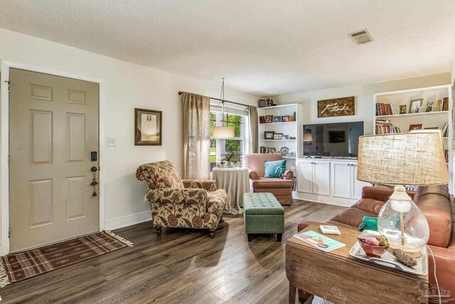 dining room with hardwood / wood-style flooring, built in shelves, and a textured ceiling