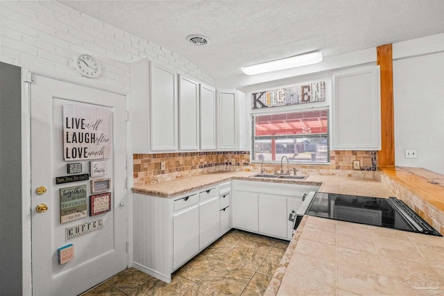 kitchen with backsplash, black stove, and white cabinets