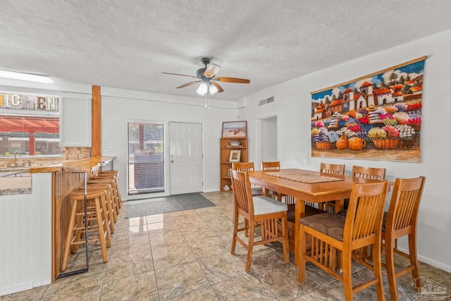 dining area with ceiling fan, a healthy amount of sunlight, a textured ceiling, and sink