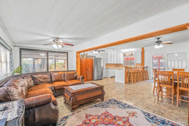 tiled living room featuring ornamental molding and ceiling fan