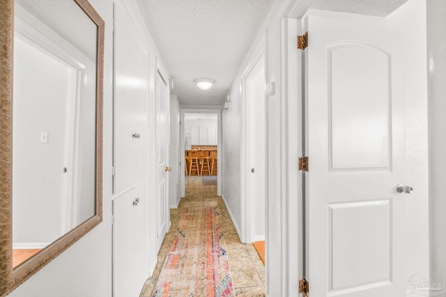 hall featuring a textured ceiling and light tile patterned flooring