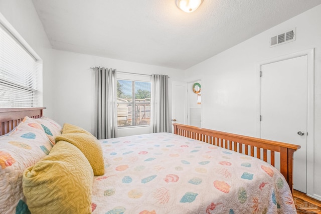 bedroom featuring a textured ceiling, vaulted ceiling, and hardwood / wood-style floors