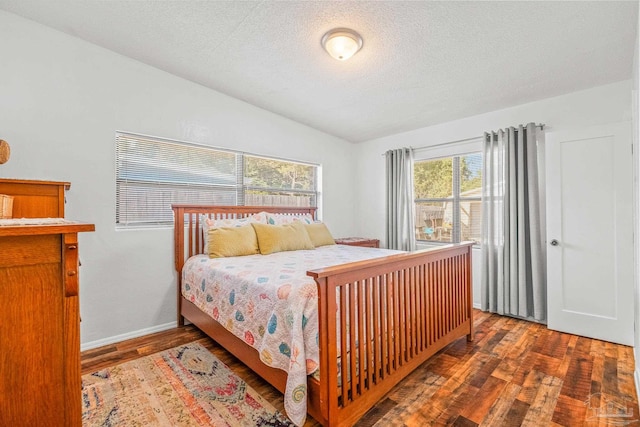 bedroom featuring vaulted ceiling, a textured ceiling, and dark hardwood / wood-style flooring