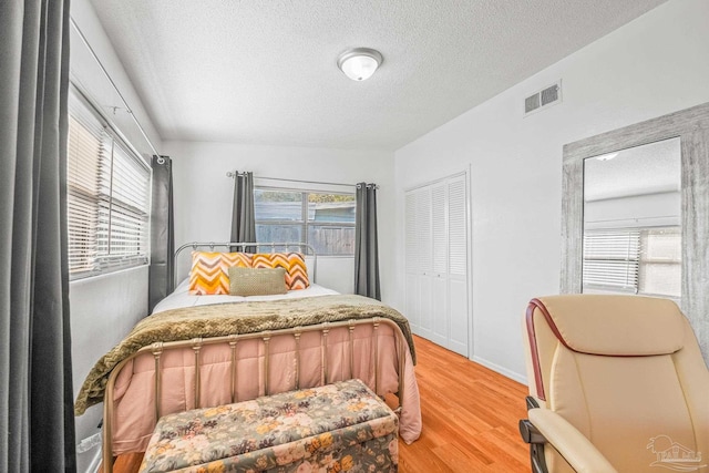 bedroom featuring a textured ceiling, wood-type flooring, and multiple windows