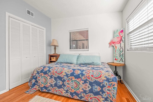 bedroom featuring light hardwood / wood-style flooring, a textured ceiling, and a closet