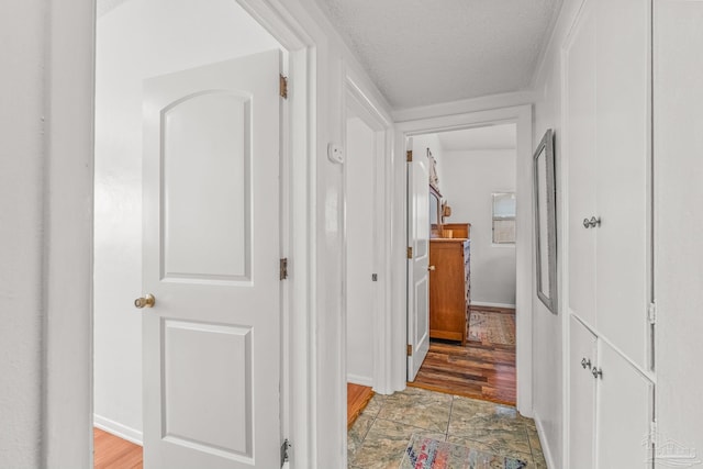 corridor with wood-type flooring and a textured ceiling