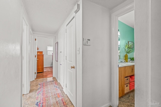 hallway with light hardwood / wood-style floors and a textured ceiling