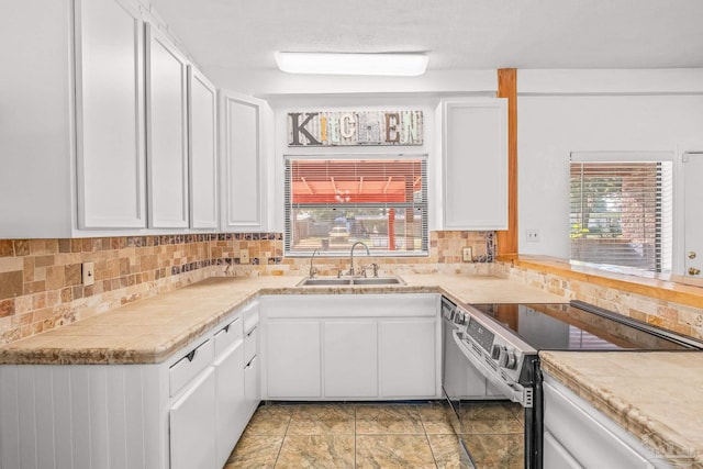 kitchen featuring stainless steel electric stove, decorative backsplash, sink, and white cabinets