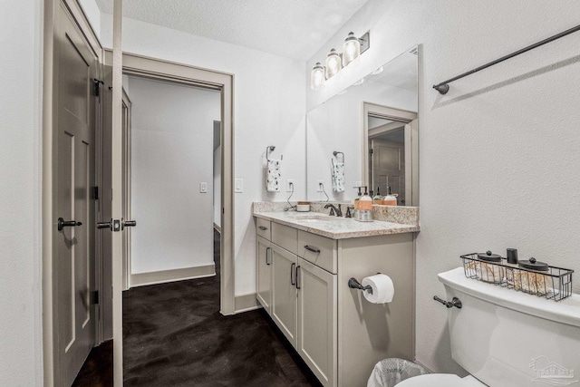 bathroom with vanity, toilet, and a textured ceiling