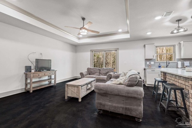 living room featuring ceiling fan, a raised ceiling, and a textured ceiling