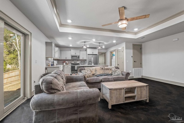 living room with a raised ceiling, sink, and ceiling fan