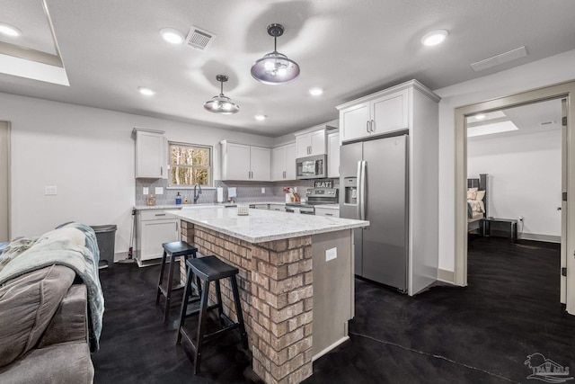 kitchen featuring stainless steel appliances, decorative light fixtures, a center island, and white cabinets