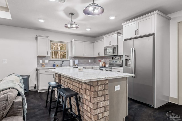 kitchen featuring white cabinetry, stainless steel appliances, a kitchen island, and hanging light fixtures