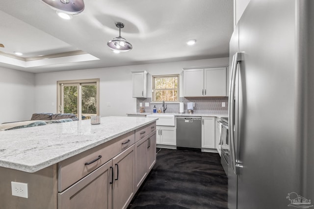 kitchen featuring a raised ceiling, white cabinetry, sink, decorative backsplash, and stainless steel appliances