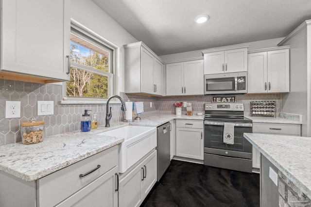 kitchen featuring stainless steel appliances, white cabinetry, and decorative backsplash