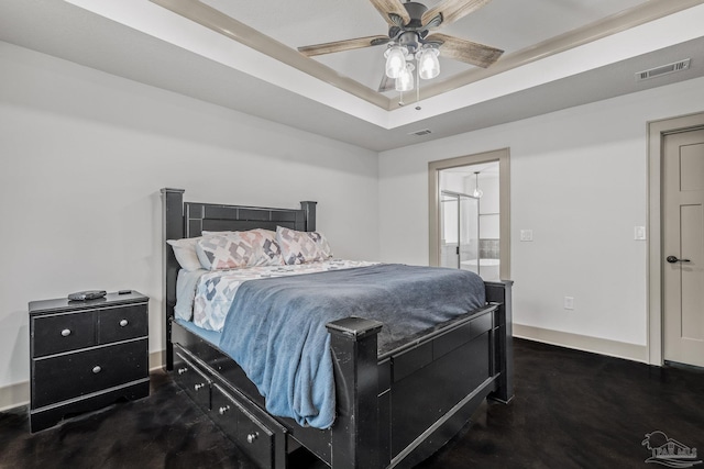 bedroom with ceiling fan, a raised ceiling, and ensuite bath